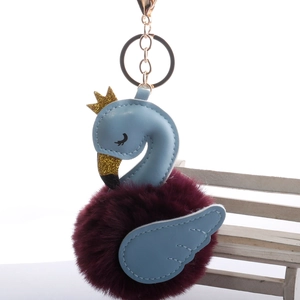 Detailed close-up of light blue swan faux fur pom pom keychain with gold glitter crown