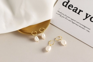 Detail shot of four s925 silver gold-plated hoop earrings with natural baroque pearls