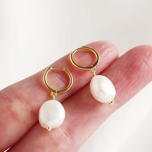 Close-up of gold s925 silver hoop earring with irregular white baroque pearl drop