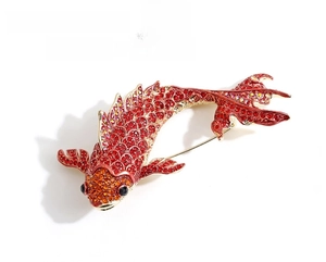 Detailed view of koi fish brooch with red and orange rhinestones in gold plating