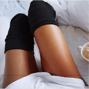 Detailed close-up of black ribbed knit over-knee socks with soft texture and cozy home vibe