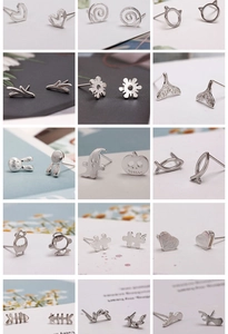 Macro display of diverse silver earring studs including heart, ghost, and leaf designs