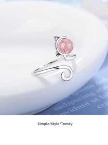 Close-up of cat-eared ring featuring a pink strawberry crystal on a white surface
