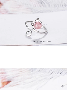 Macro detail of silver cat ring featuring a pink strawberry crystal bead on white card