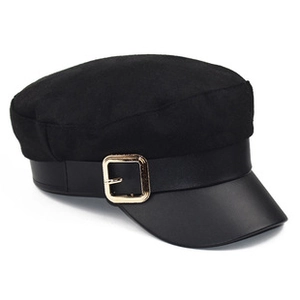 Detail of black baker boy hat featuring a PU leather brim and a gold square metal buckle