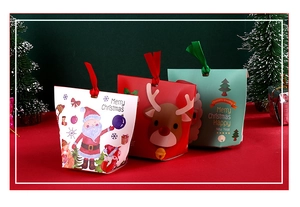 Detail of Christmas gift bags in red and green with ribbon handles and festive trees