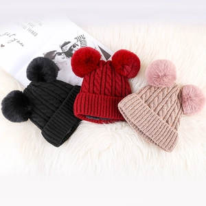 Detailed knit texture of winter beanies with fluffy double faux fur pom-poms on soft faux fur