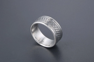 Détail d'une bague large argentée avec texture en relief de type écailles en acier inoxydable