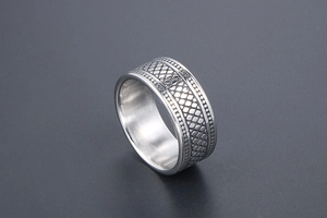 Macro d'une bague en acier inoxydable argenté avec texture écailles de serpent et perles