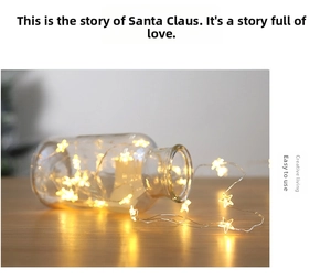 Detail of warm white LED star fairy lights inside a clear glass jar on a wooden desk