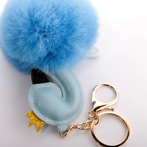 Detailed shot of sky blue flamingo plush ball keychain with golden crown and metal hardware