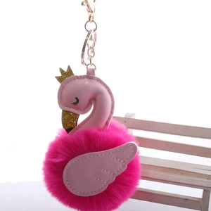 Detail of flamingo pom-pom keychain with pink wings, gold crown and metallic lobster clasp