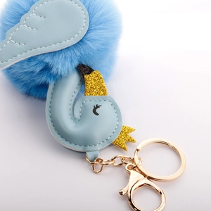 Detail of light blue swan faux fur pompom keychain with golden crown and lobster clasp