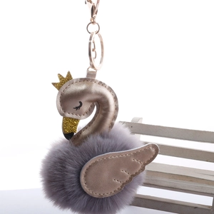 Detail of grey-purple faux fur swan keychain with gold crown and plush puff ball