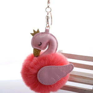 Detail of pink swan plush keychain featuring gold crown and faux leather wings