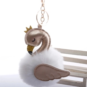 Close-up of elegant swan keychain with white faux fur ball and golden crown detail