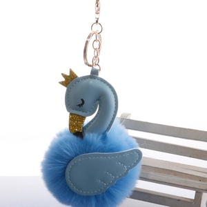 Sky blue swan fluffy keychain with golden crown and glitter beak on white chair