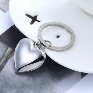 Polished heart-shaped stainless steel keychain on a white decorative plate
