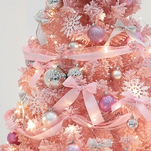 Rosa beflockter Weihnachtsbaum mit silberner Deko, Satinbögen und warmweißen LED-Lichtern