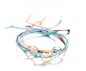 Dettaglio di bracciali bohémien in corda cerata intrecciata con ciondoli a montagna oro e argento