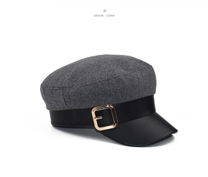 Close-up of wool baker boy hat featuring black leather strap and gold metal buckle detail