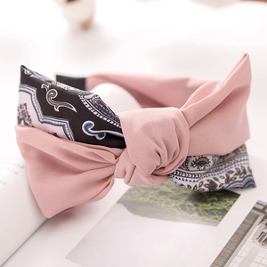 Detail of pink and paisley fabric bow headband on an open magazine with soft lighting