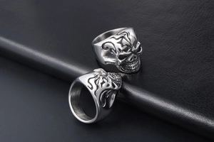 Macro close-up of polished stainless steel gothic skull rings on black leather texture