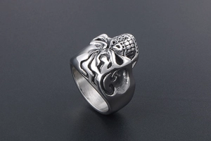 Detailed view of silver skull ring with flame embossed patterns on dark background