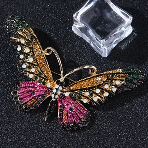 Close-up of vibrant enamel butterfly brooch with colorful rhinestones on black background