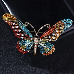 Macro shot of colorful rhinestones set on a gold butterfly brooch with a black leather background