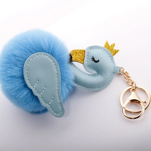 Detailed view of light blue swan keychain with golden crown and fluffy faux fur pompom