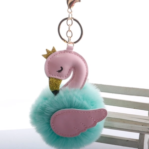 Detailed view of mint green fluffy pompom swan keychain with golden crown and pink wings