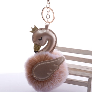 Close-up of pink faux fur swan keychain with golden crown and metallic ring
