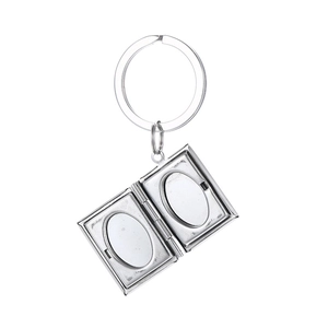 Detailed macro view of an open silver book-shaped locket keychain with dual photo slots