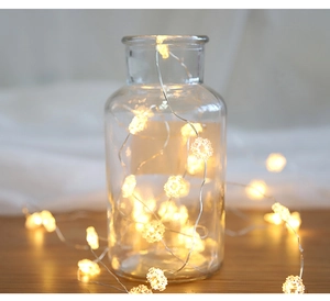 Close-up of warm white LED snowflake string lights arranged inside a clear glass jar