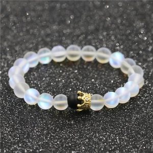Matte moonstone bead bracelet with gold crown charm on black glitter surface