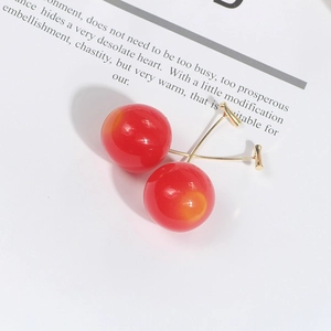 Macro shot of glossy red cherry earrings with elegant gold-plated stems on white background