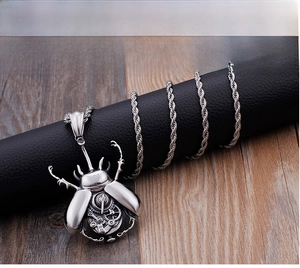 Macro shot of mechanical gear details on beetle pendant with silver rope chain necklace