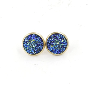 Close-up of 12mm round gold-plated stud earrings with sparkling blue resin inlay