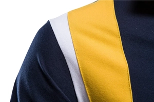 Detail of navy, white, and yellow patchwork polo shirt shoulder with premium stitching