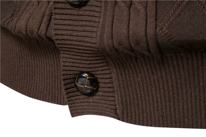 Close-up of brown knit cardigan featuring dark cross-pattern buttons and ribbed hem detail