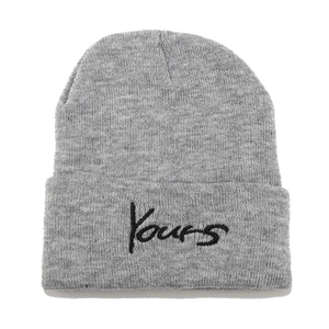 Detail of grey knitted beanie featuring black YOURS letter embroidery on the folded cuff