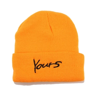 Close-up of orange wool knit beanie featuring Yours embroidered letter on the cuff