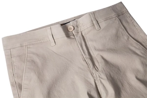 Detailed macro view of the waistband, button closure and pockets of beige cotton trousers