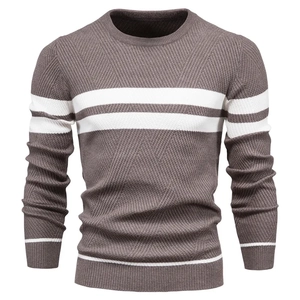 Close-up of brown knit sweater featuring white stripes and textured geometric knit patterns