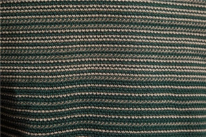 Gros plan sur la texture tricotée à rayures vertes et brunes d'un pull vintage ajusté