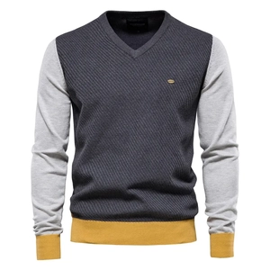 Detail of V-neck men's knit sweater with grey patchwork and mustard yellow ribbed cuffs