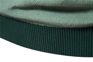 Detailed macro view of the two-tone green knit fabric and ribbed hem of the sweater