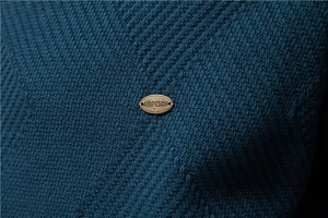Gros plan sur un tricot bleu foncé avec un badge métallique doré de style vintage