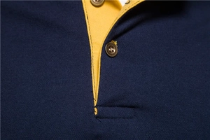 Detailed close-up of navy piqué polo collar with yellow lining and metal buttons